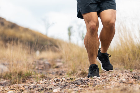 Close up foot trail runner man running on rocky mountain. Athlete jog exercising outdoor for...