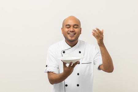 Smiling Young handsome asian man chef in uniform gesture smelling empty plate delicious dish menu good taste on isolated. Cooking  man Occupation chef or baker People in kitchen restaurant and hotel.の写真素材