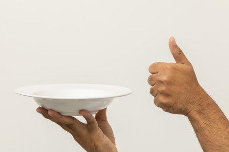 Close up hand chef showing empty plate delicious dish menu good taste thumbs up on isolated white background. Cooking man Occupation chef or baker People in kitchen restaurant and hotel.の写真素材