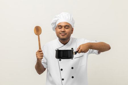 Smiling Young man chef in uniform gesture smelling empty hot pot stew soup delicious dish menu good taste on isolated. Cooking man Occupation chef People in kitchen restaurant and hotel.の写真素材