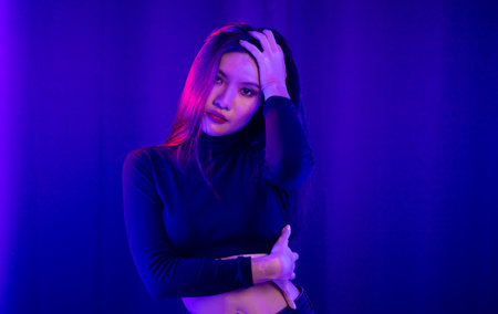 Stylish sexy woman in trendy. Beautiful young asian woman standing pose with neon light. Asia Pretty...