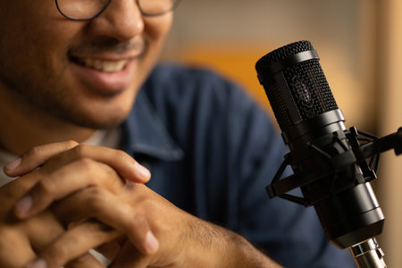 Young asian man host streaming podcast with condenser microphone work on laptop at small broadcast home studio. Content creator blogger recording voice over radio interview guest conversationの写真素材