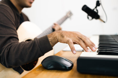 Close up hands songwriter playing piano keyboard and guitar in home studio. Professional musician audio equipment at Recording studio.の写真素材