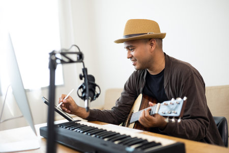 Professional Musician song writer with condenser microphone note on tablet. Hispanic male composing...