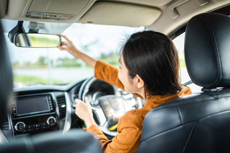 Young beautiful asian women getting new car. she very happy and excited hand adjust the rearview...