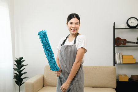 Young beautiful woman with apron and rubber glove with mop ready for cleaning home. Housekeeping...