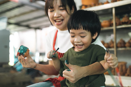 Happy family moment Mother teaching son how to painting mug cup ceramic workshop. Child creative activities and art. Kid playing  pottery workshop. Developing children's learning skills.の写真素材