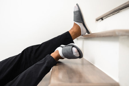 A young man faints and collapses on the stairs of the house. He was injured in an accident and fell down the stairs. He was alone in the house not being helped by anyone. Broken boneの写真素材