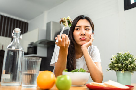 Unhappy female looking to organic greens vegetable salad in weight loss diet and wellness on table....