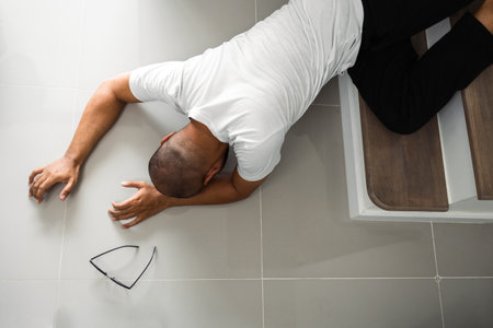 A young man faints and collapses on the stairs of the house. He was injured in an accident and fell down the stairs. He was alone in the house not being helped by anyone. Broken boneの写真素材