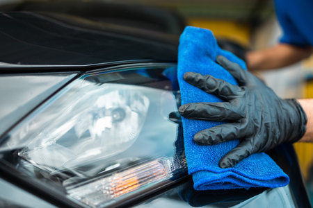 Man worker washing car service with micro fiber. Car wash cleaning wipe station. Employees clean a vehicle professionally detailing.の写真素材