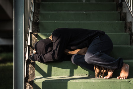 Poor tired stressed depressed hungry homeless man in the shadow city. Homeless man sitting on the street waiting for help food and money from people volunteer foundation donate.の写真素材