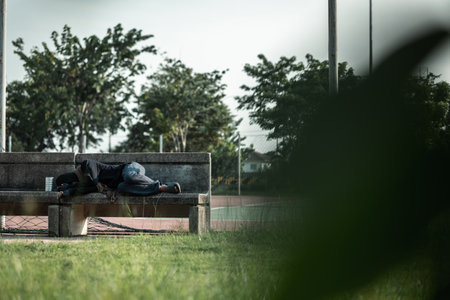 Poor tired stressed depressed hungry homeless man in the shadow city. Homeless man sitting on the...