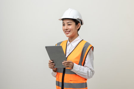 Asian engineer worker woman or architect with white safety helmet standing on isolated white background. Mechanic service factory Professional job occupation in uniform working with tabletの写真素材