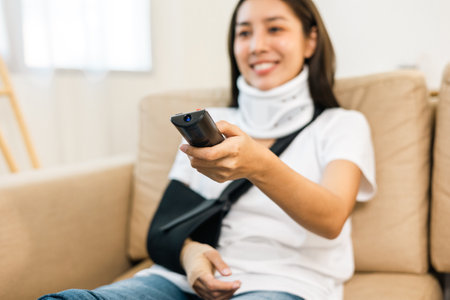 Happy woman recovery watching tv using remote from accident fracture broken bone injury with leg...