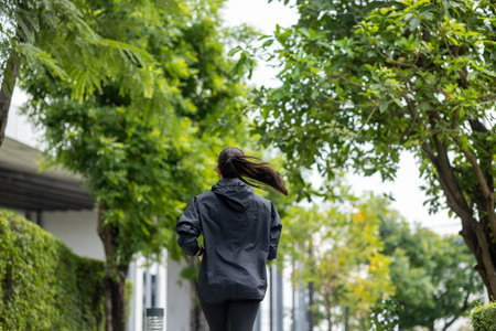 Happy slim woman wearing sportswear jogging in the city at sunrise. Young beautiful asian female in sports bra running outdoor. Workout exercise in the morning. Healthy and active lifestyle concept.の写真素材