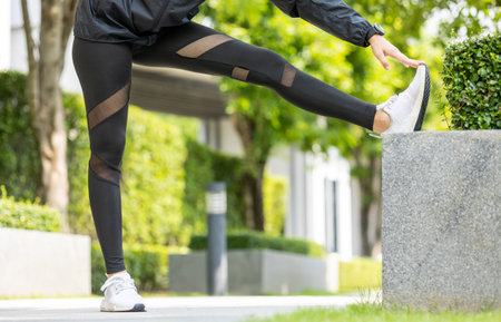 Healthy and fit asian woman wearing sportswear warming up in the park at sunrise. Confident young...