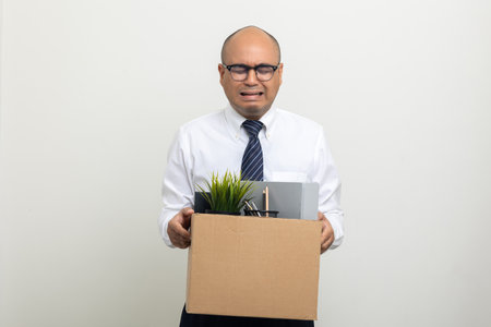 Businessman with box cardboard packing personal items after losing jobs. Failure businessman standing on isolated background. Your fired Unemployed Jobless People Crisisの写真素材
