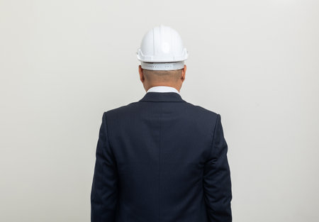 Rear view Businessman manager owner real estate on isolated white background. Cooperation of architect designer. Engineer with safety helmet checking at working construction siteの写真素材