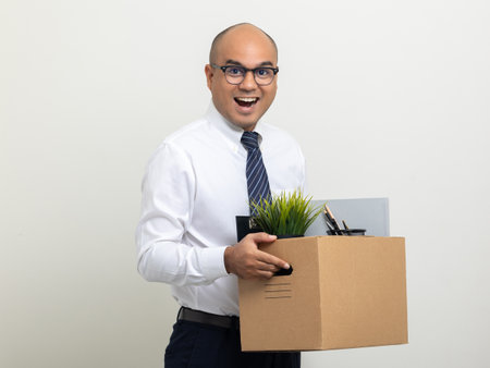 Employee first day working in the office. Happy Businessman with box cardboard personal item getting new jobs. Young man start working new office standing on isolated white background.の写真素材