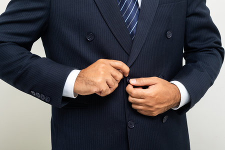 Confident businessman buttoning or adjust classic blue suit on isolated white background. Handsome man wearing a nice suitの写真素材