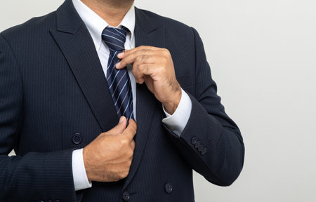 Confident businessman buttoning or adjust classic blue suit on isolated white background. Handsome man wearing a nice suitの写真素材