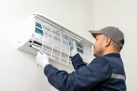 Air conditioner service indoors. Air conditioner cleaning technician He opened the front cover and took out the filters and washed it. He in uniform wearing rubberの写真素材
