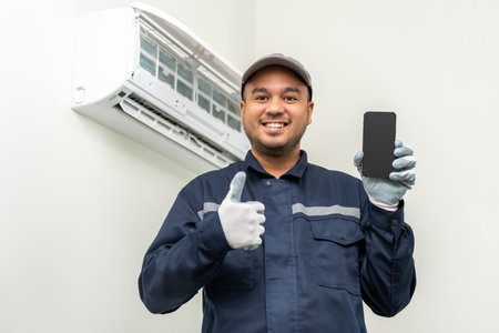 Air conditioner call service by cell phone. Air conditioner cleaning technician He opened the front cover and took out the filters and washed it. Holding smartphoneの写真素材
