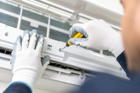 Air conditioner service indoors. Air conditioner cleaning technician He opened the front cover and took out the filters and washed it. He in uniform wearing rubberの写真素材