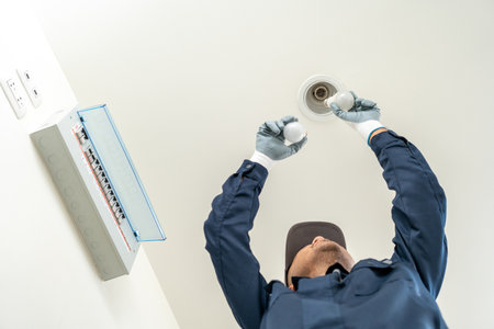 Electrician installing led light bulbs at home for power saving. Fixing changing the Light Inside apartment. Home service concept.の写真素材