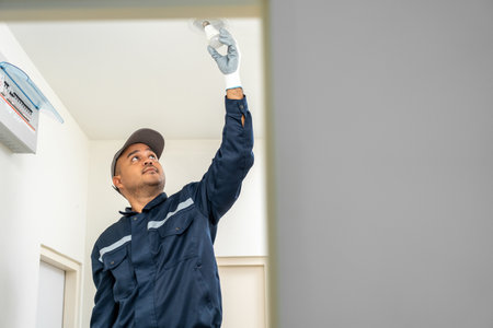 Electrician installing led light bulbs at home for power saving. Fixing changing the Light Inside apartment. Home service concept.の写真素材