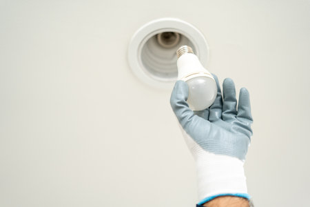Electrician installing led light bulbs at home for power saving. Fixing changing the Light Inside apartment. Home service concept.の写真素材