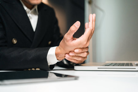 Businessman hand get hurt and pain in hand. Symptom office syndrome. He has symptom stress in his hand stiffness causing inconvenience.の写真素材