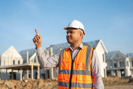 Confident engineer handsome man at modern home building construction. Architect with white safety...