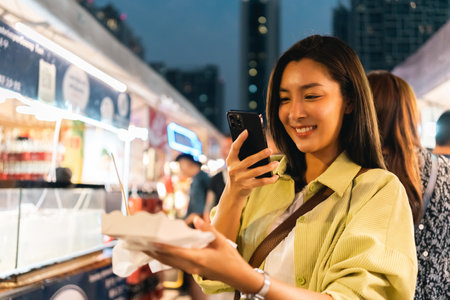 Asian woman enjoy eating fries street food at night market. Traveler Asian blogger women Happy tourists Beautiful female with Traditional thailand bangkok food.の写真素材