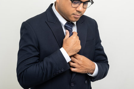 Confident businessman buttoning or adjust classic blue suit on isolated white background. Handsome...