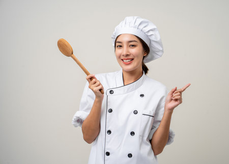Young beautiful asian woman chef in uniform holding ladle utensils cooking in the kitchen various gesture delicious dish menu good taste on isolated. Cooking woman chef people in kitchen restaurantの写真素材