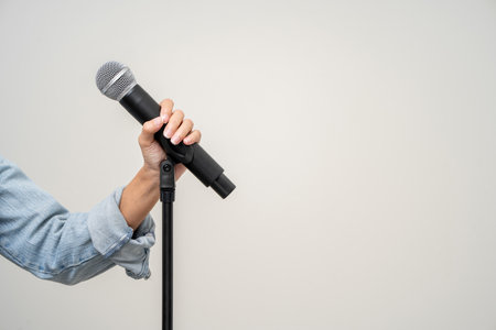 Close up woman hand holding High quality dynamic microphone and singing song or speaking talking with people on isolated white background. Woman testing microphone voice for interviewの写真素材