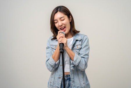 Happiness young asian woman singing song. Artist vocalist singer on isolated background. Confident woman public speaking talking with microphone in studio.の写真素材