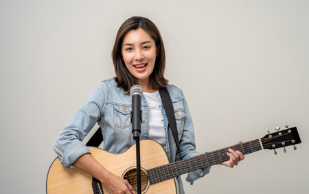 Happiness young asian woman singing song with guitar. Artist vocalist singer on isolated background. Confident woman public speaking talking with microphone in studio.の写真素材