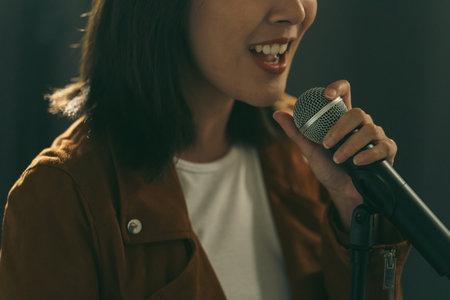 Close up woman hand holding High quality dynamic microphone and singing song or speaking talking with people on isolated white background. Woman testing microphone voice for interviewの写真素材