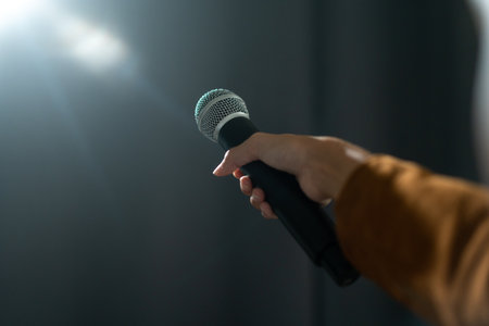 Close up woman hand holding High quality dynamic microphone and singing song or speaking talking with people on isolated white background. Woman testing microphone voice for interviewの写真素材