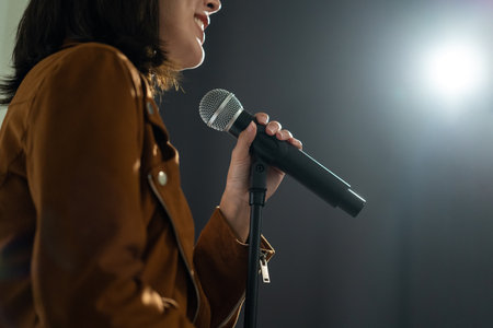 Close up woman hand holding High quality dynamic microphone and singing song or speaking talking with people on isolated white background. Woman testing microphone voice for interviewの写真素材
