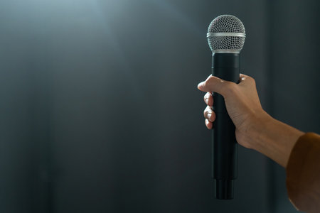 Close up woman hand holding High quality dynamic microphone and singing song or speaking talking with people on isolated white background. Woman testing microphone voice for interviewの写真素材