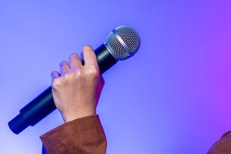 Attractive singer woman singing music on stage with spotlight strike through the darkness at concert event. Musician performing live with neon light in hall.の写真素材