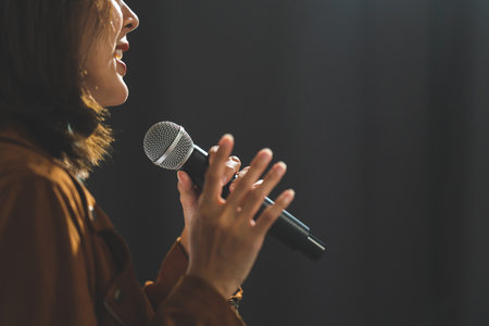 Close up woman hand holding High quality dynamic microphone and singing song or speaking talking with people on isolated white background. Woman testing microphone voice for interviewの写真素材