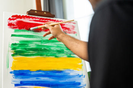 Asian man artist working on painting with brush and variant acrylic color. Man artist painter on canvas in creative studio as art conceptの写真素材