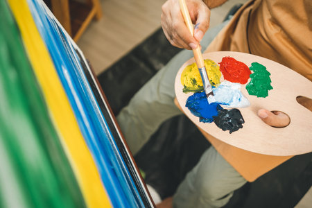 Asian man artist working on painting with brush and variant acrylic color. Man artist painter on canvas in creative studio as art conceptの写真素材