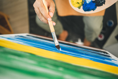 Asian man artist working on painting with brush and variant acrylic color. Man artist painter on canvas in creative studio as art conceptの写真素材