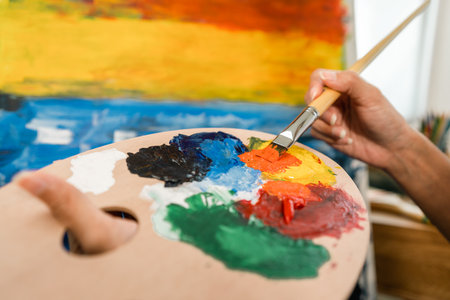 Close up hand Asian woman artist working on painting with brush and variant acrylic color. Female artist painter on canvas in creative studio as art conceptの写真素材